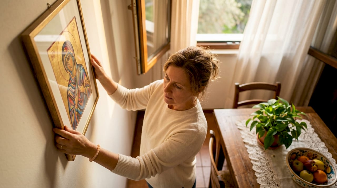 Woman hanging Christian artwork in living room