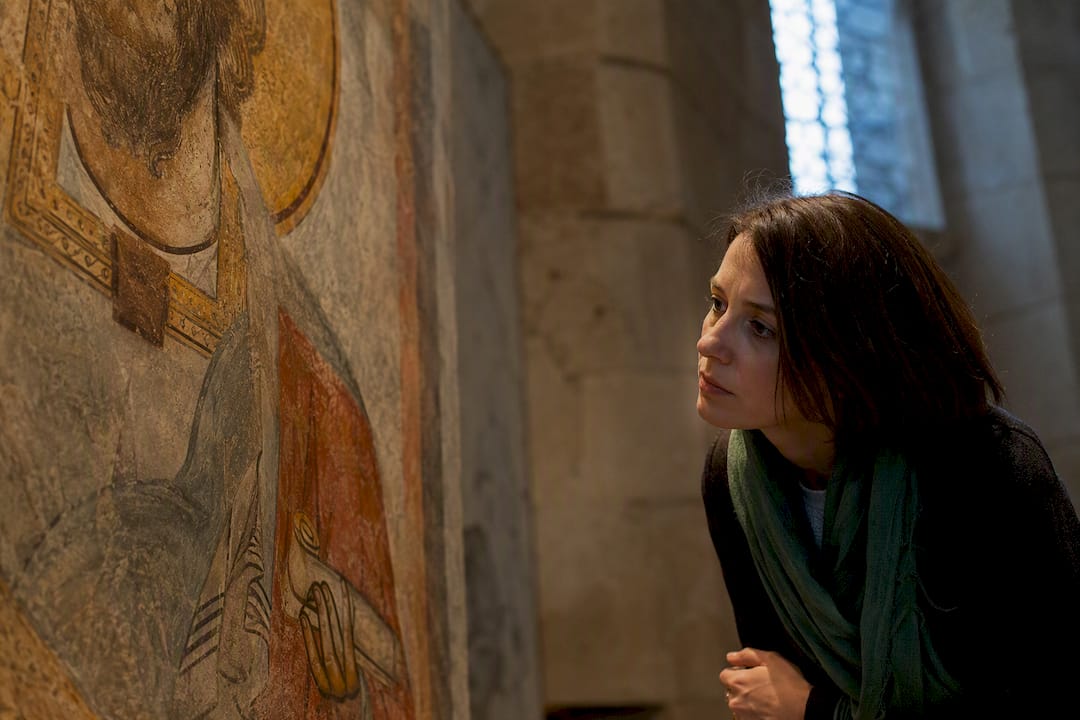 Visitor studying saint fresco details