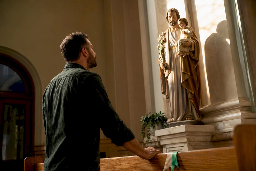 Father praying before a Saint Joseph statue