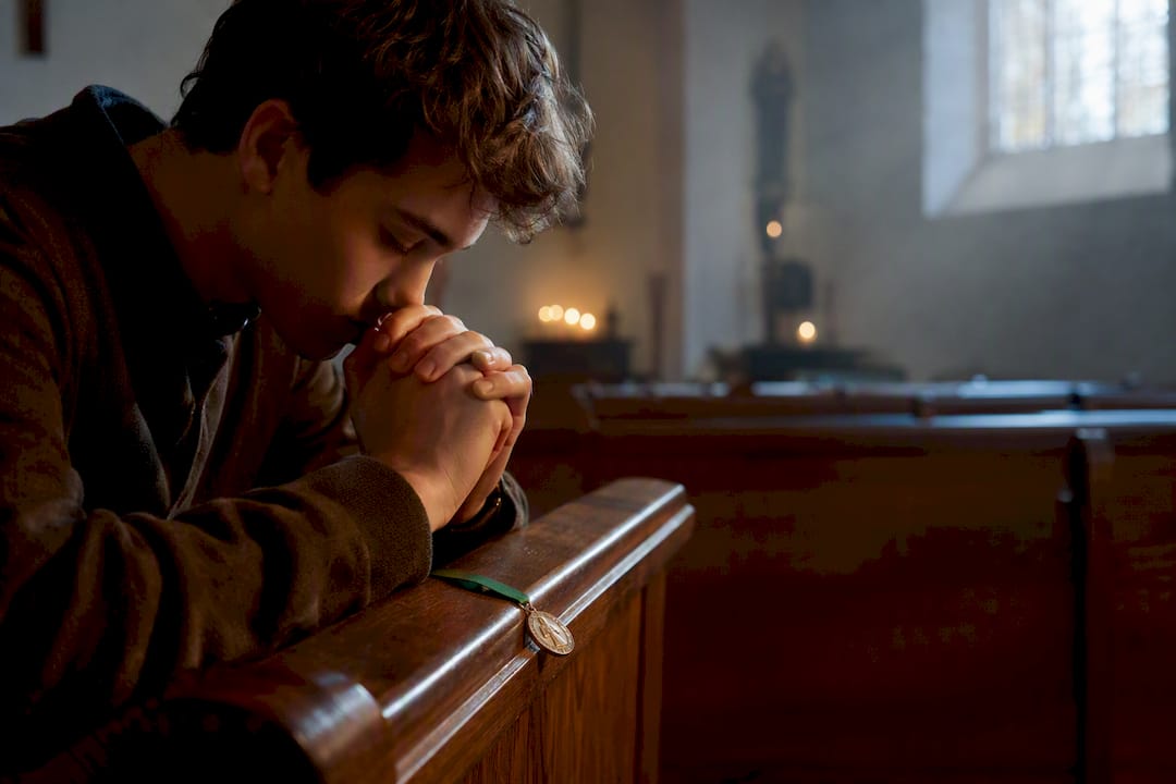 Student praying in a chapel before exams